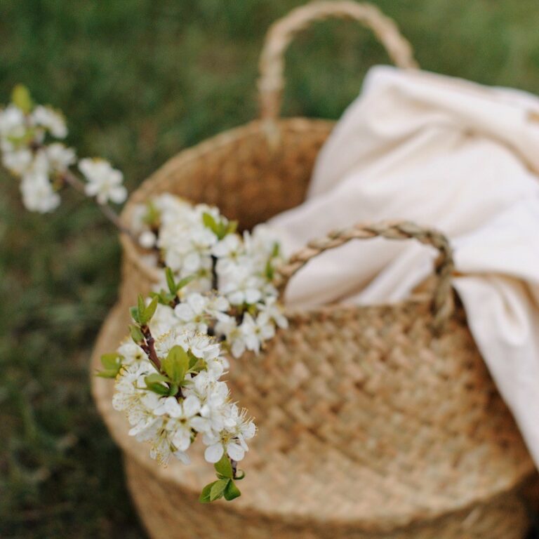 Geflochtener Korb mit weißen Blüten und weißer Leinendecke dekoriert